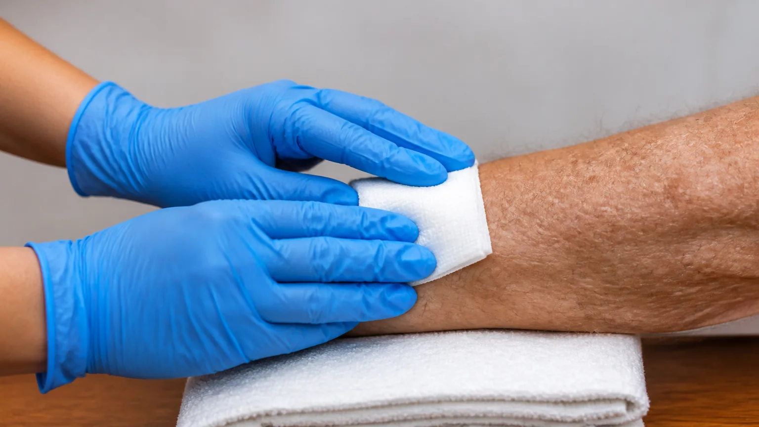 Nurse holding gauze on an older man's forearm