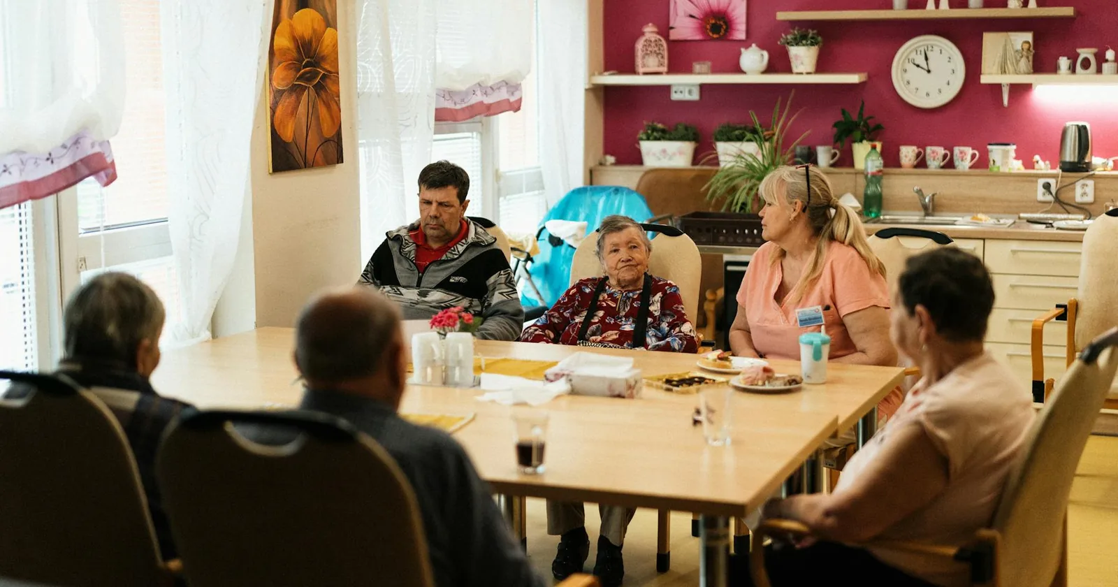 Seniors enjoying a meal together in a senior living community dining room with caregivers.