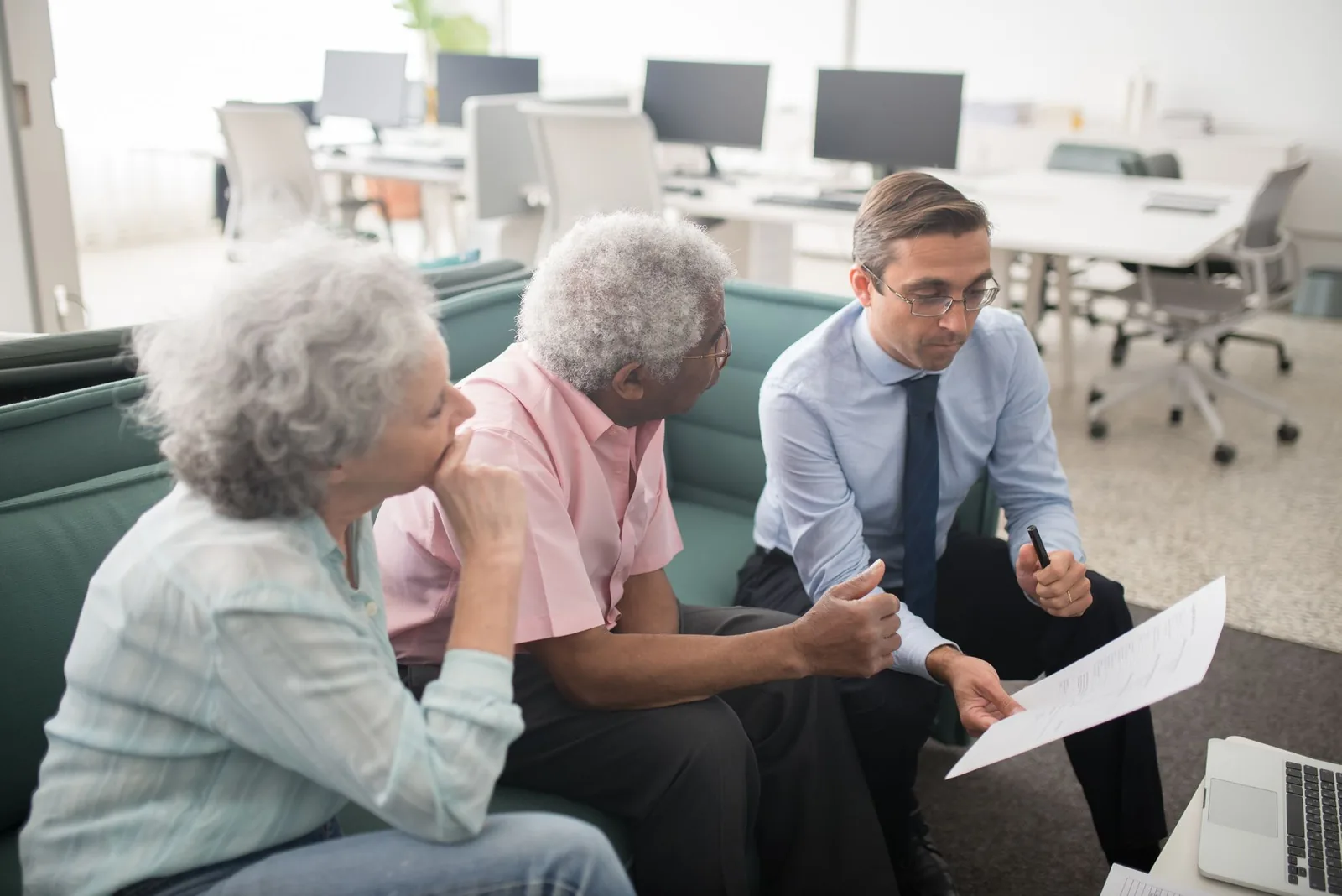 An older couple sitting with a senior care advisor at a table, reviewing options and asking questions about local communities.